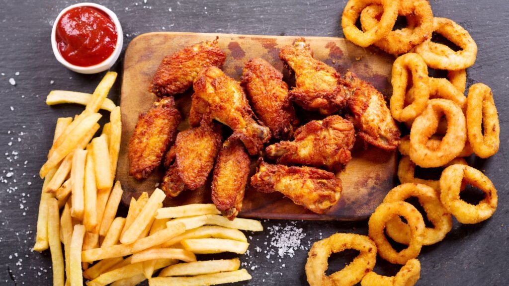 a wooden board with fried chicken wings and fries