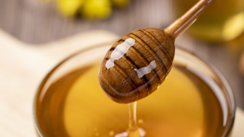 a honey dipper dripping from a bowl of honey